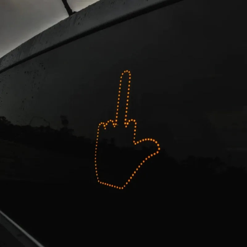 Black plastic LED gesture car light with amber LEDs showing a hand gesture, remote control, and 3M tape for mounting.