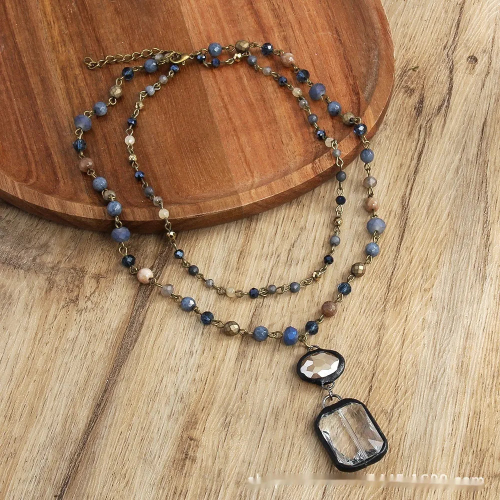 Two-layer tribal necklace with stone and glass pendants on a chain, shown in beige and blue.