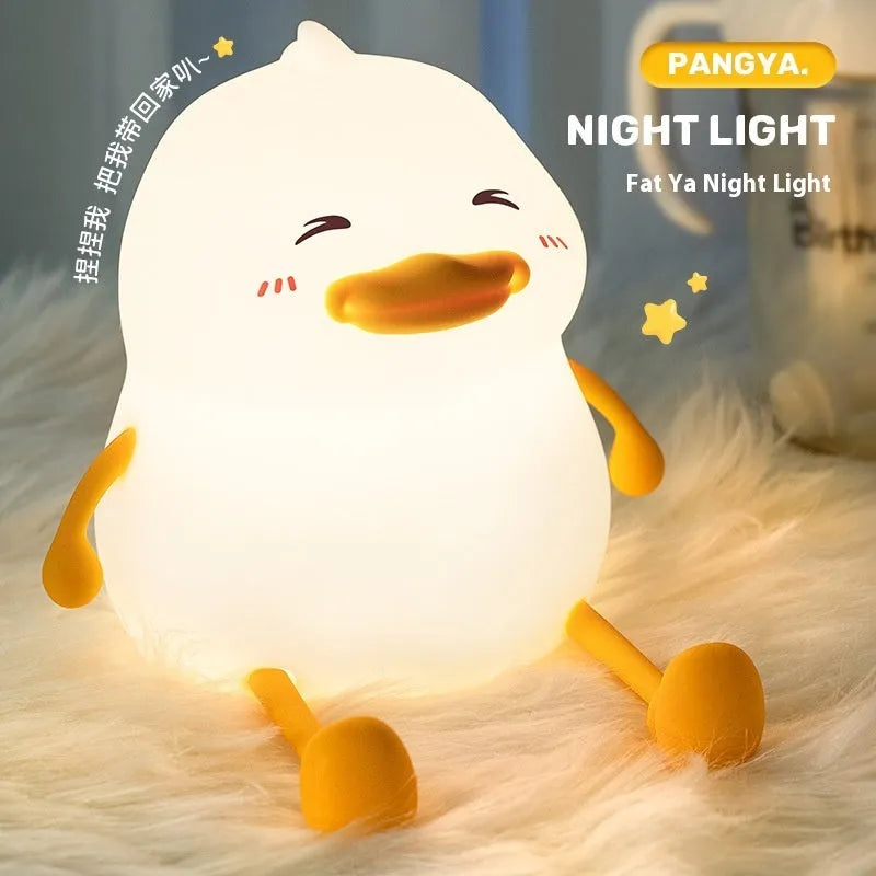 Chubby white silicone rechargeable night light on a wooden desk surface.