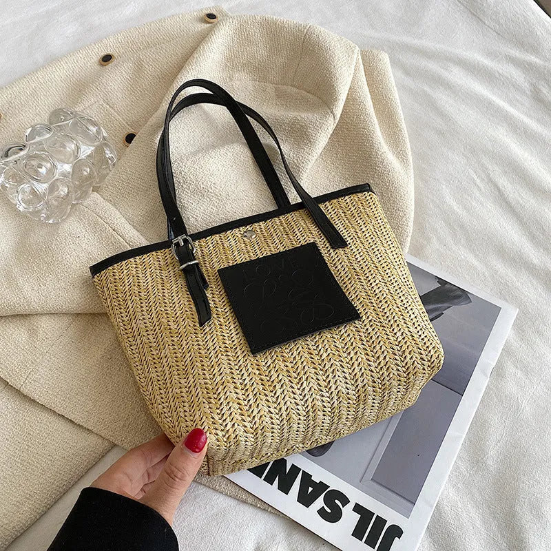 Women's straw woven shoulder bag with PU trim showing tapered shape and sewn thread details