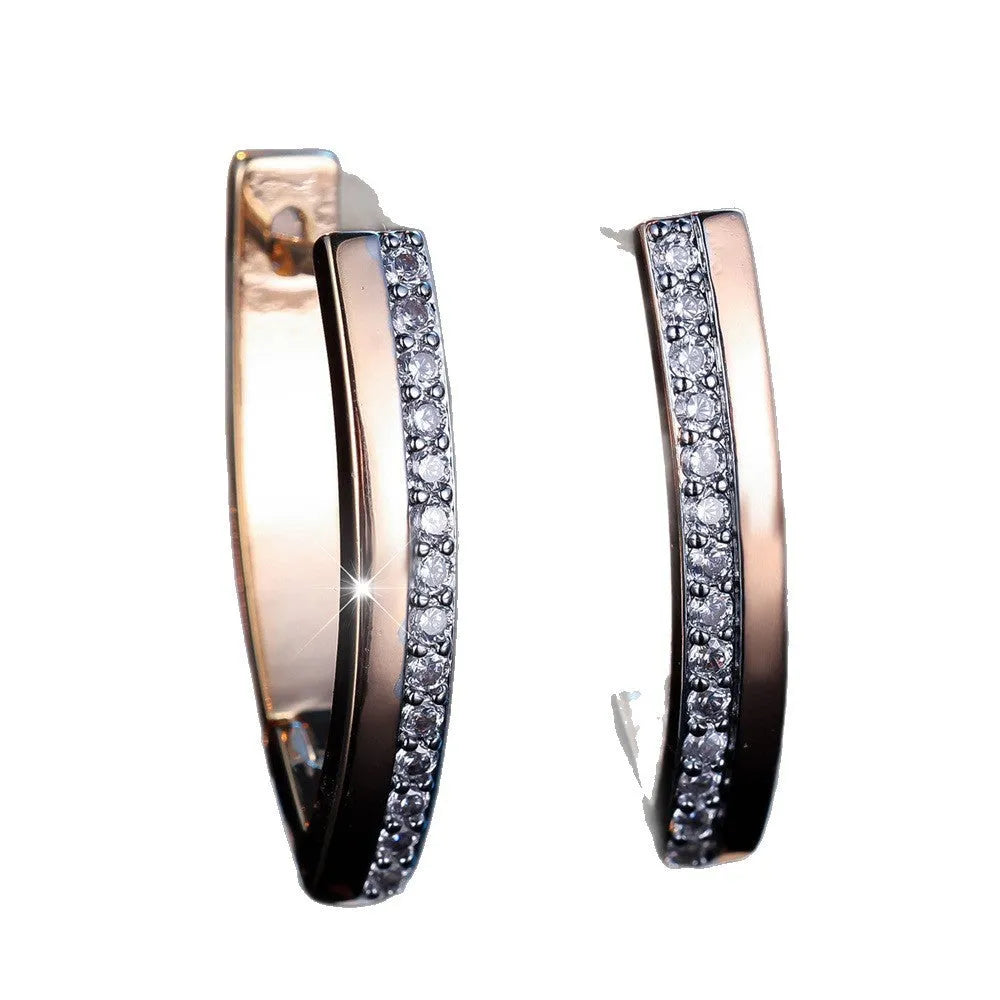 Close-up of women's geometric V-shaped clip-on earrings in champagne gold with white diamond details on a copper base.