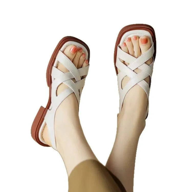 Glossy black patent leather women's sandals with a cross-band design, square toe, and low rubber sole.