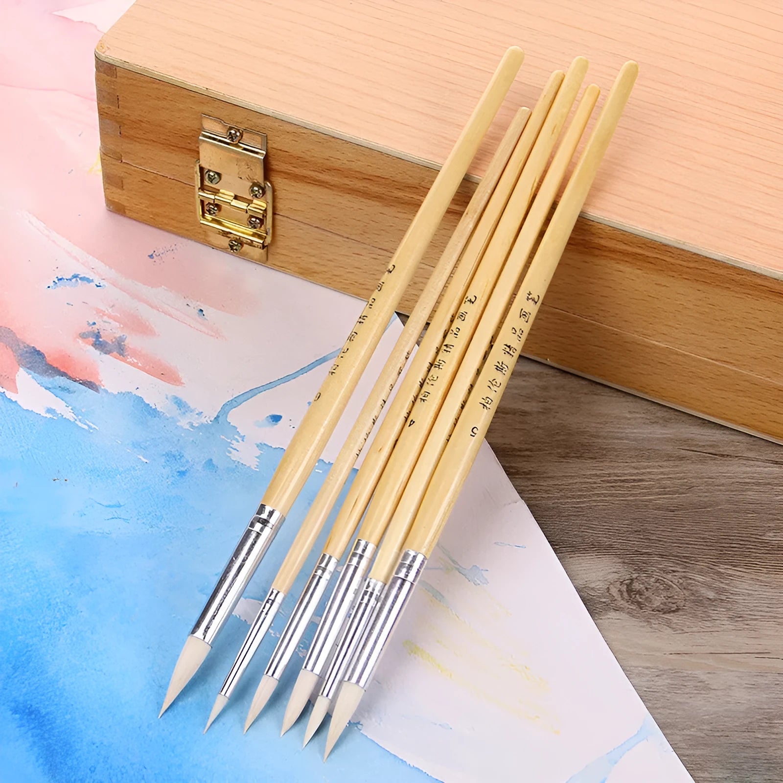 Six wooden-handled artist brushes with pointed wool tips arranged together.