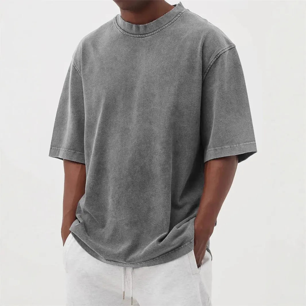 Man wearing a loose-fit, stone-washed grey t-shirt with a distressed solid colour finish and half sleeves.