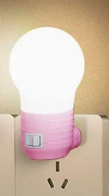 Plug-in bedside baby night light in white shell with modern round design on a table.