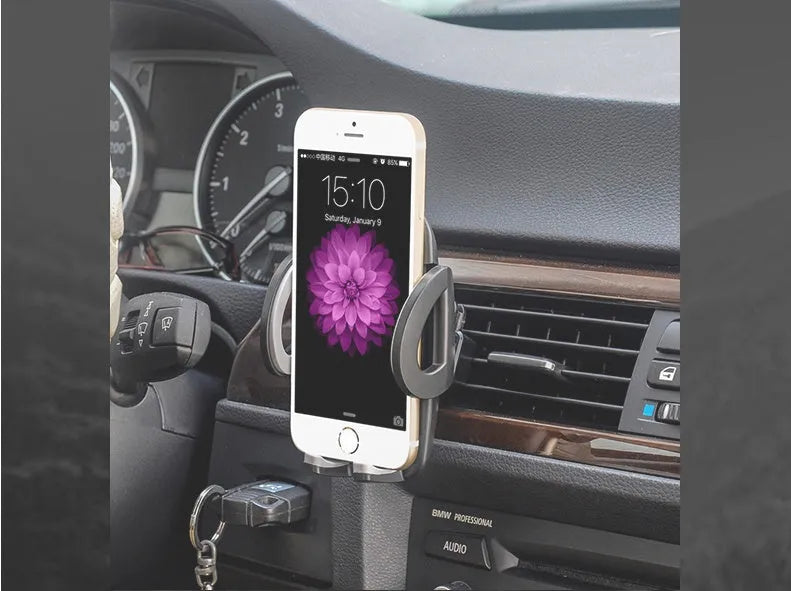 Black plastic car mobile phone holder mounted on air conditioning vent with adjustable arms gripping smartphone