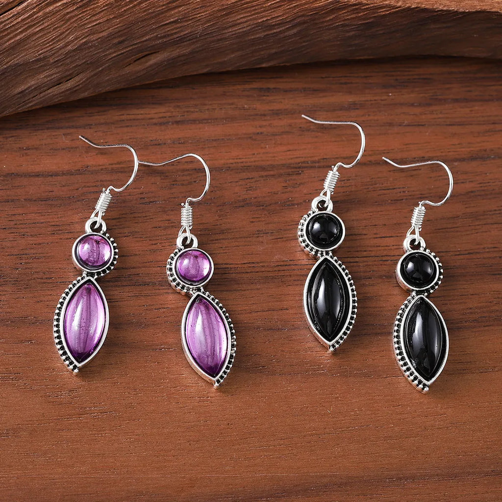 A pair of geometric vintage earrings with a black and purple electroplated finish, showing a pendant design with round elements.