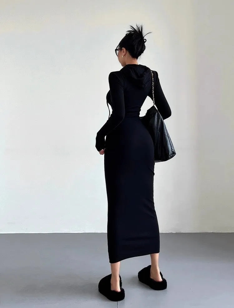 A woman wearing a light grey hooded sheath dress with long sleeves, showcasing the high waist and over-the-knee length.
