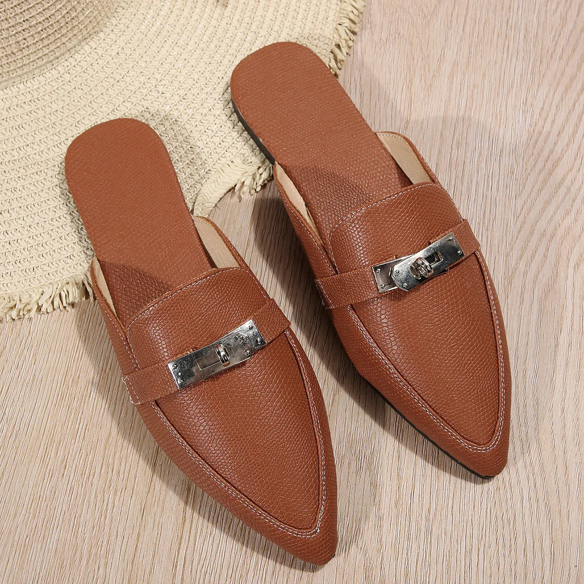Light brown women's pointed toe low heel slippers with a rubber sole on a plain background.