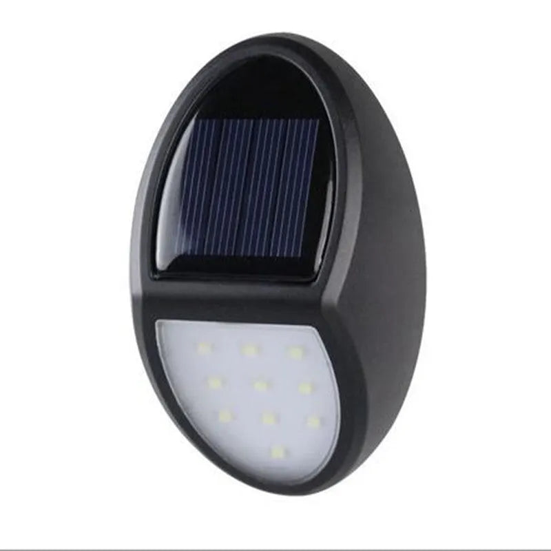 Black rectangular LED solar-powered outdoor wall light mounted on a fence.