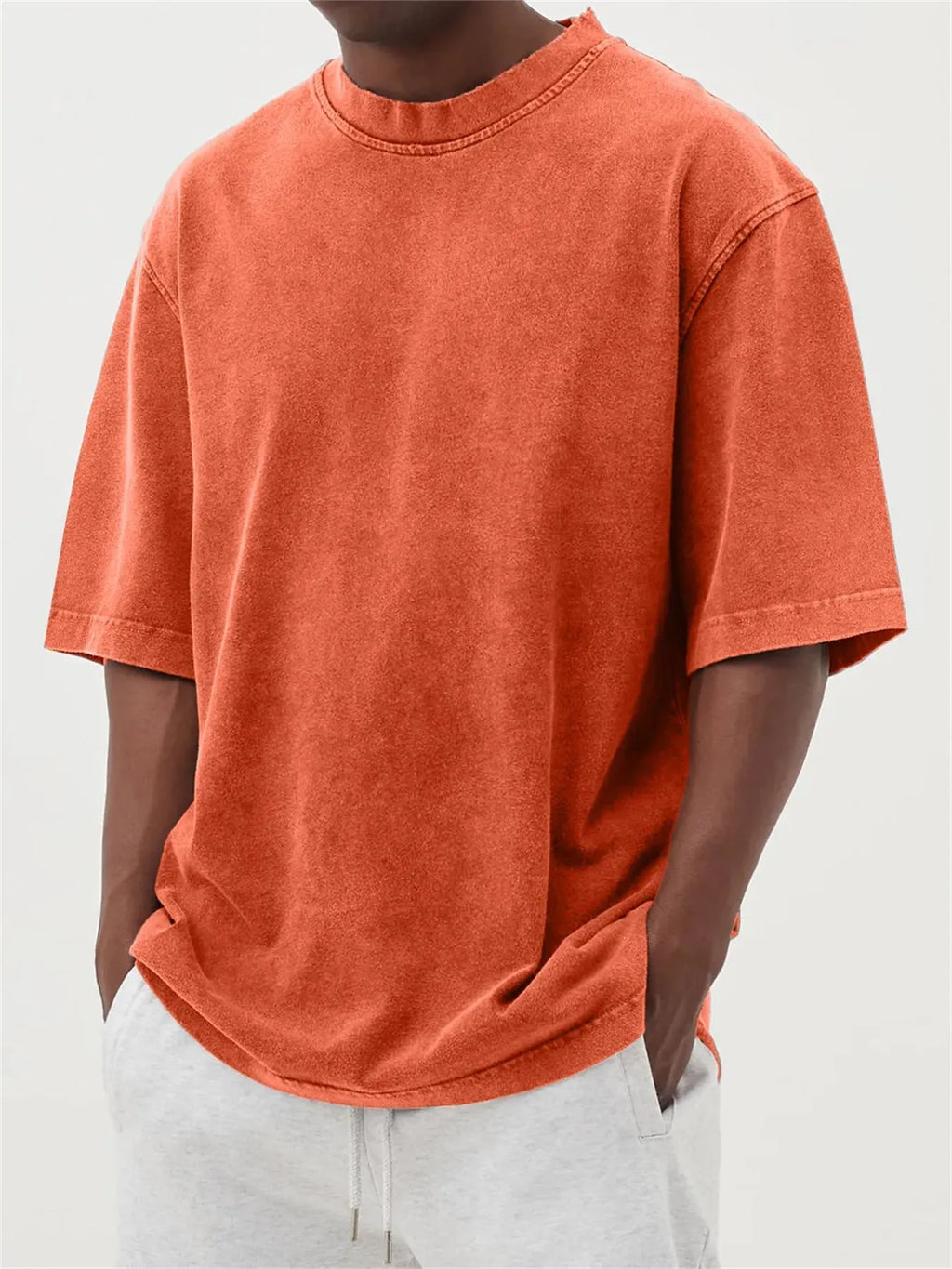 Man wearing a loose-fit, stone-washed grey t-shirt with a distressed solid colour finish and half sleeves.