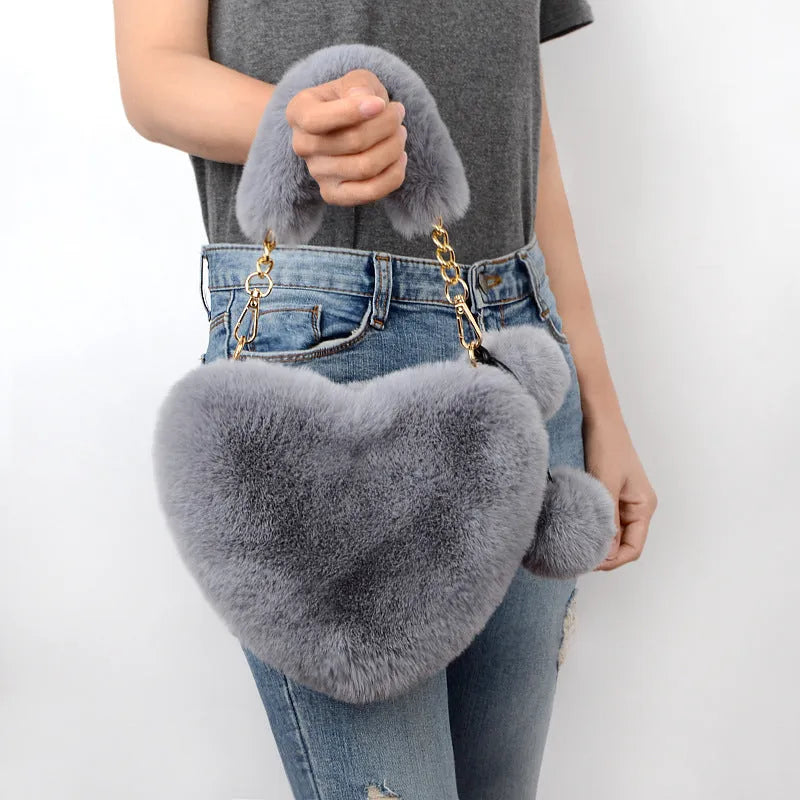 A soft, heart-shaped plush handbag for women in a medium size with a detachable shoulder strap.