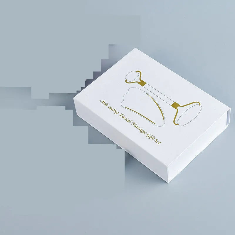 White jade double-headed facial roller and gua sha scraping tool set with a wooden storage board.