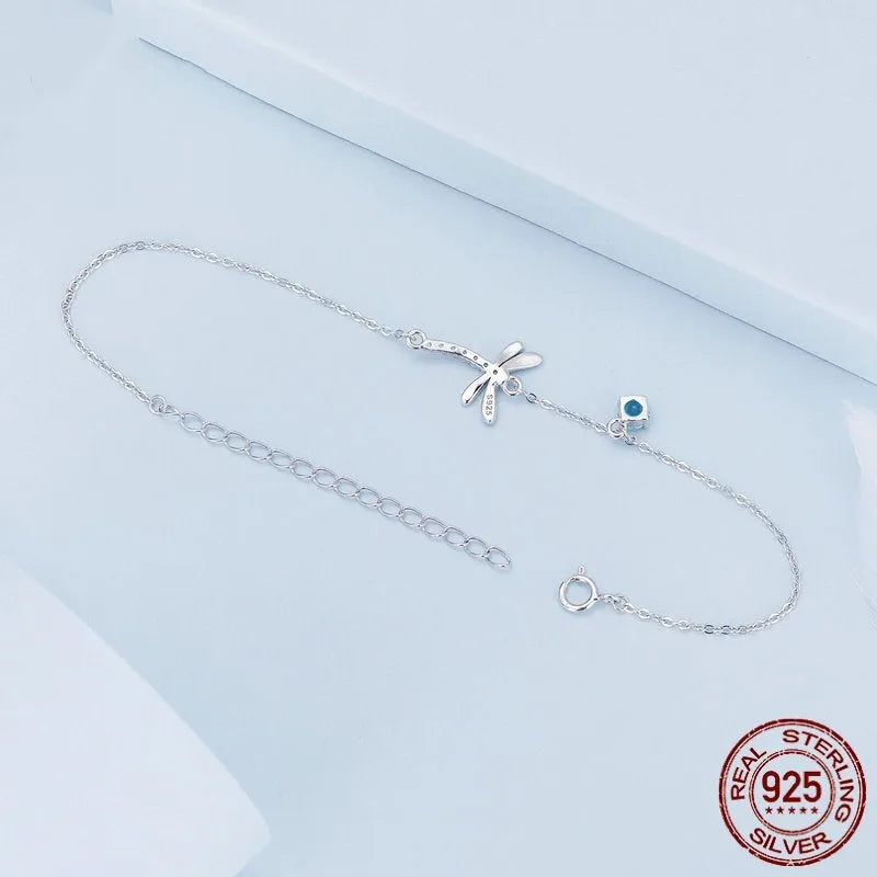 Sterling silver white gold plated dragonfly bracelet with dripping cubic zirconia stones on a light background