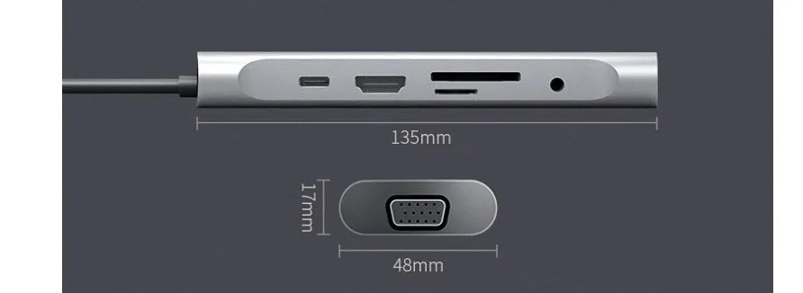 Grey aluminium USB-C docking station with HDMI, VGA, USB, and charging ports on a desk.