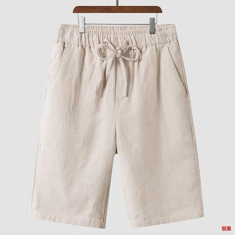 Men's beige linen casual shorts with a loose fit and cropped length on a plain background.