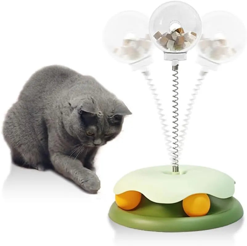 Blue or green PP plastic cat treat dispenser toy with a built-in track ball on a flat surface.