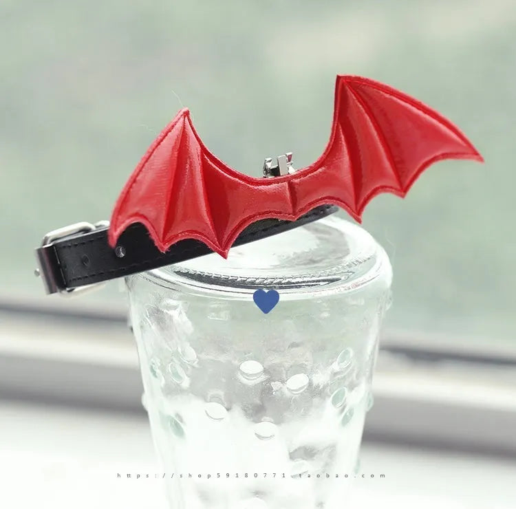 Small black patent leather dog collar with little devil wings charm and bell attached.
