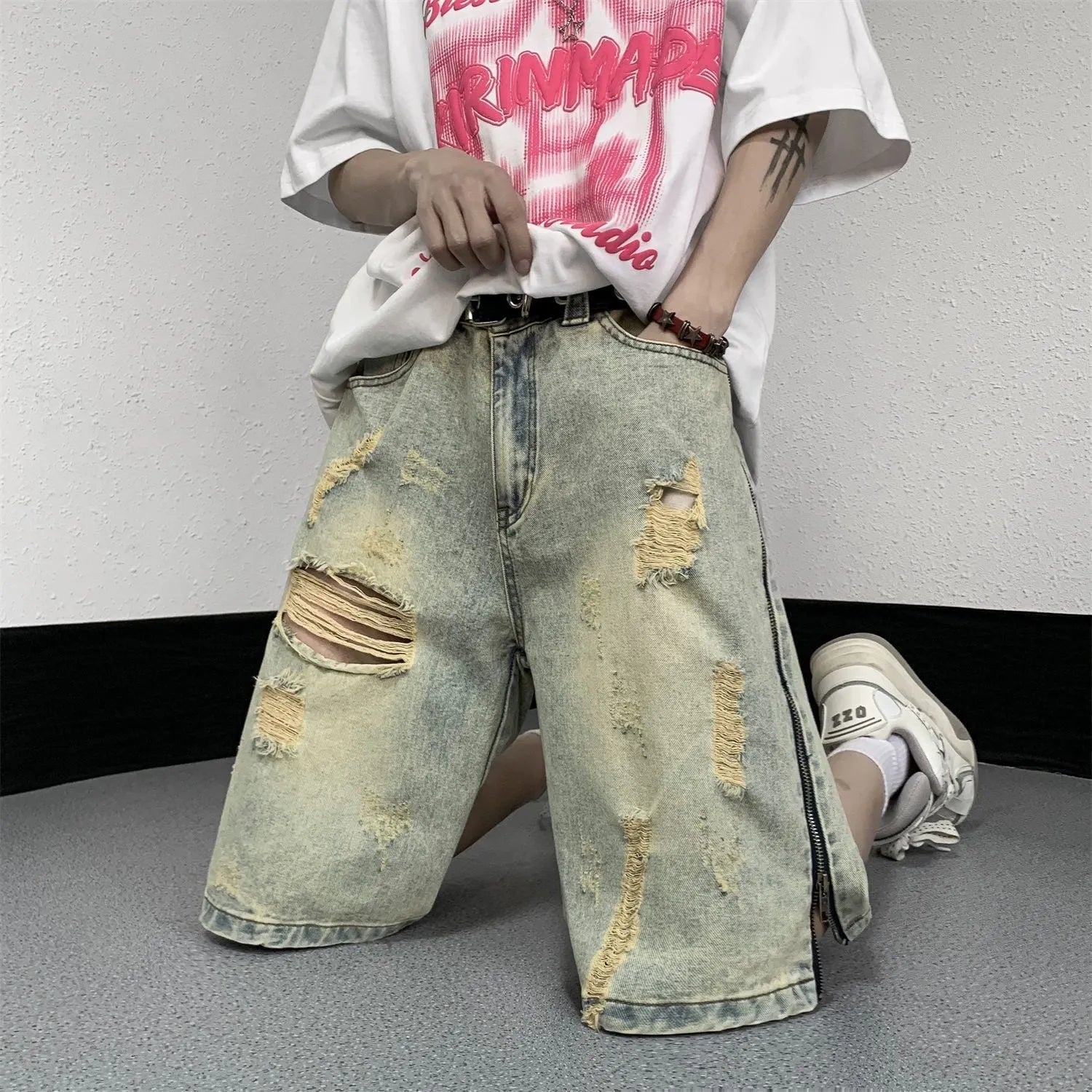 Man wearing blue distressed denim shorts with rips and a loose, straight-leg silhouette.