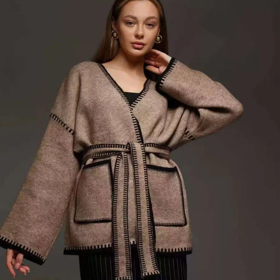 Loose fit camel coloured knitted cardigan sweater with long sleeves laid flat.