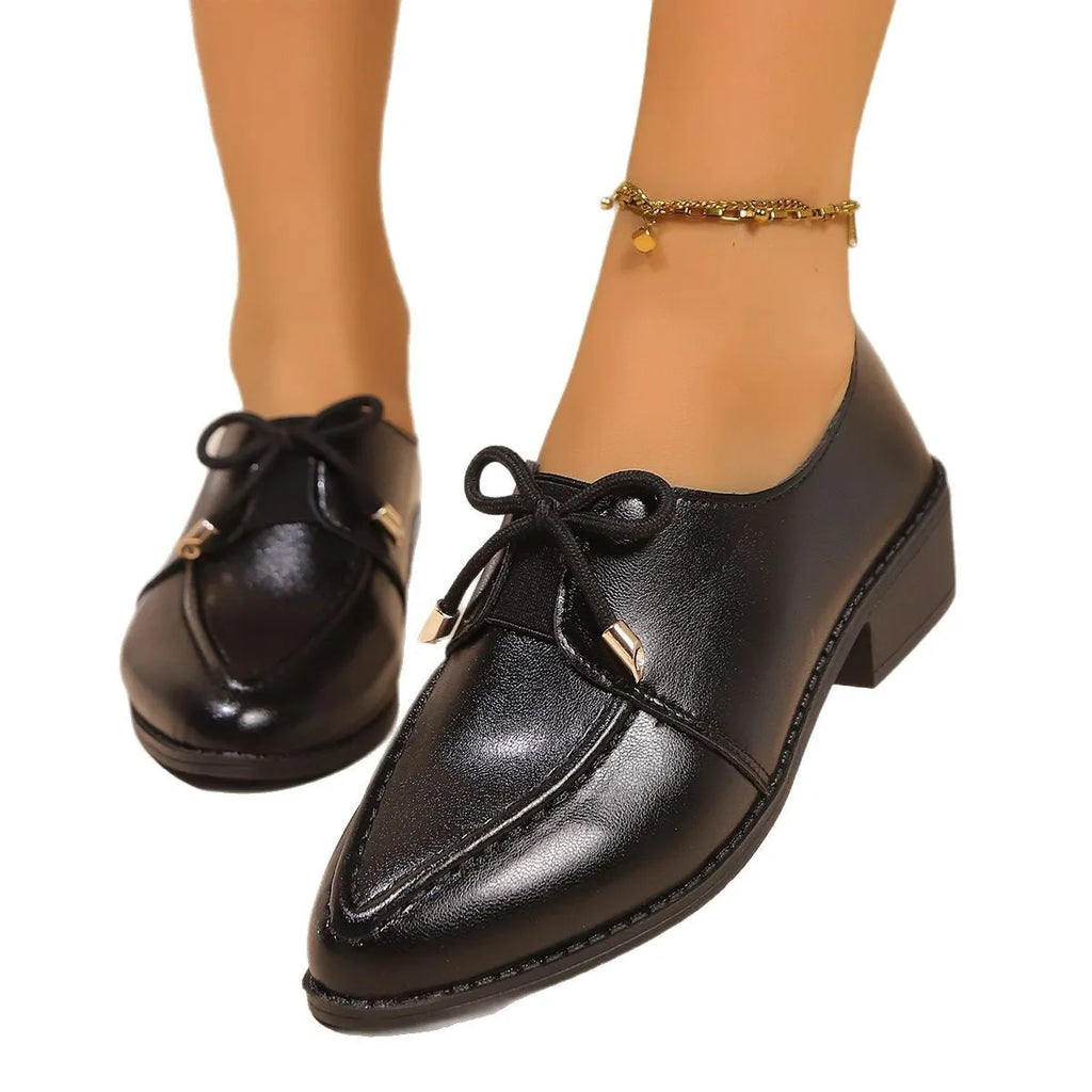 Women's British-style leather-look shoes with decorative bow detail on pointed toe