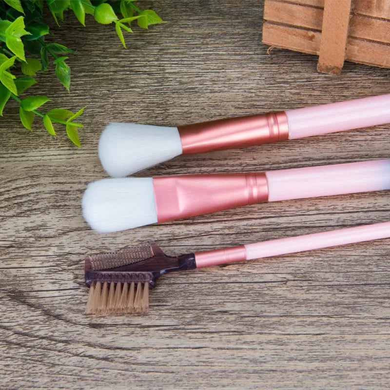 12 pink makeup brushes with synthetic hair bristles and plastic handles on a light surface