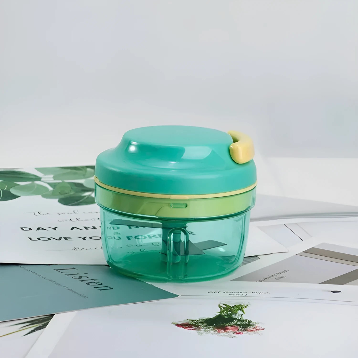 Green manual kitchen food grinder with transparent container and stainless steel blade for making baby food purees.