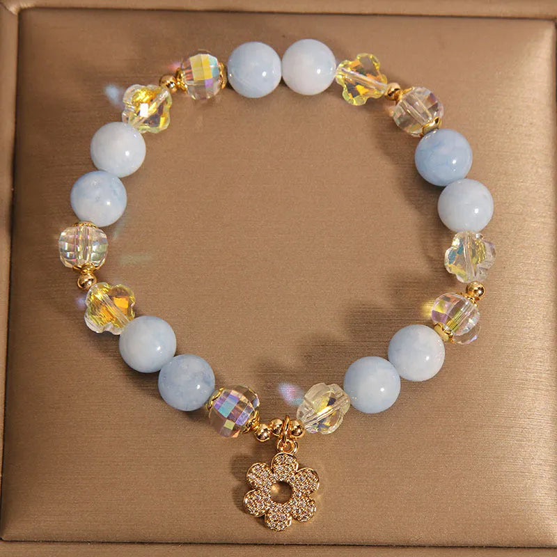 Women's aquamarine crystal bracelet featuring a four-leaf clover charm and pearl decorative elements.