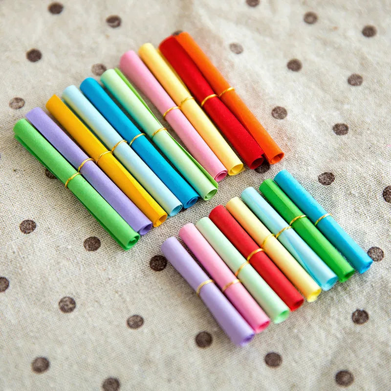 Assorted coloured miniature paper scrolls for drift bottle messages, showing pre-punched hole.