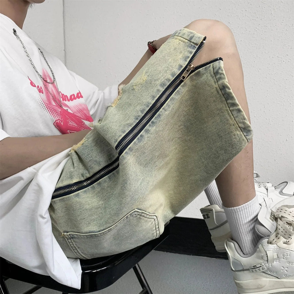 Man wearing blue distressed denim shorts with rips and a loose, straight-leg silhouette.