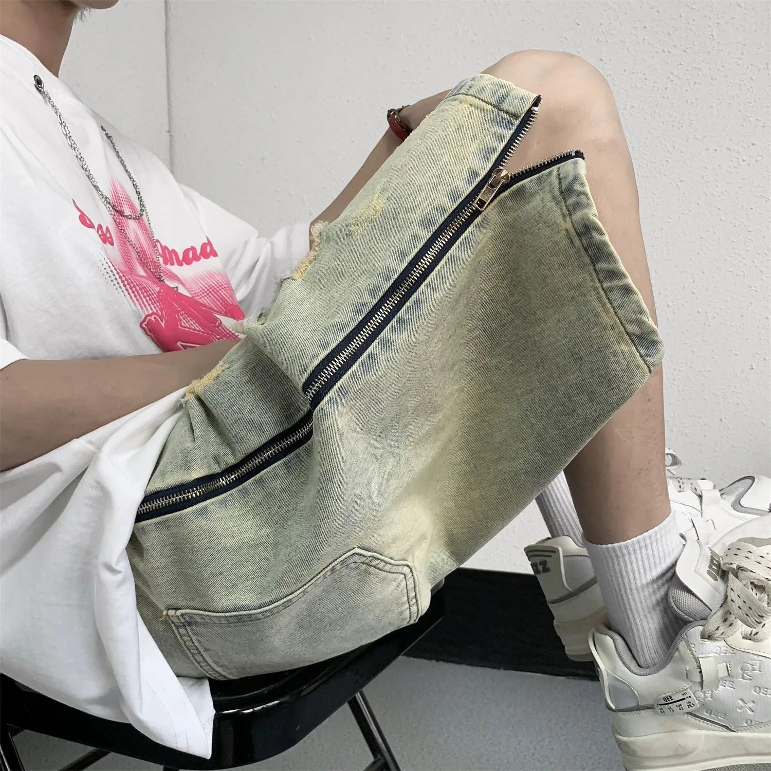 Man wearing blue distressed denim shorts with rips and a loose, straight-leg silhouette.