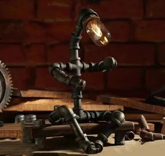 Green bronze vintage industrial iron pipe desk lamp on a wooden table.