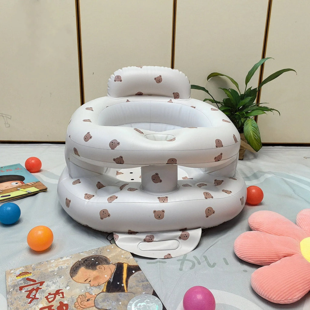 Inflatable infant dining chair in PVC with bear design, deflated beside a baby for scale