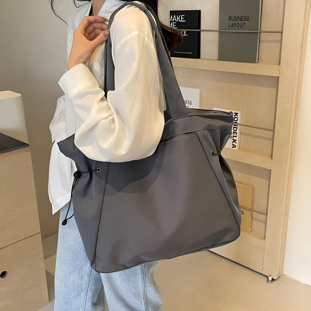 Soft folding shoulder tote bag in Oxford cloth shown in one of five colour options: black, brown, dark grey, light grey, or purple.
