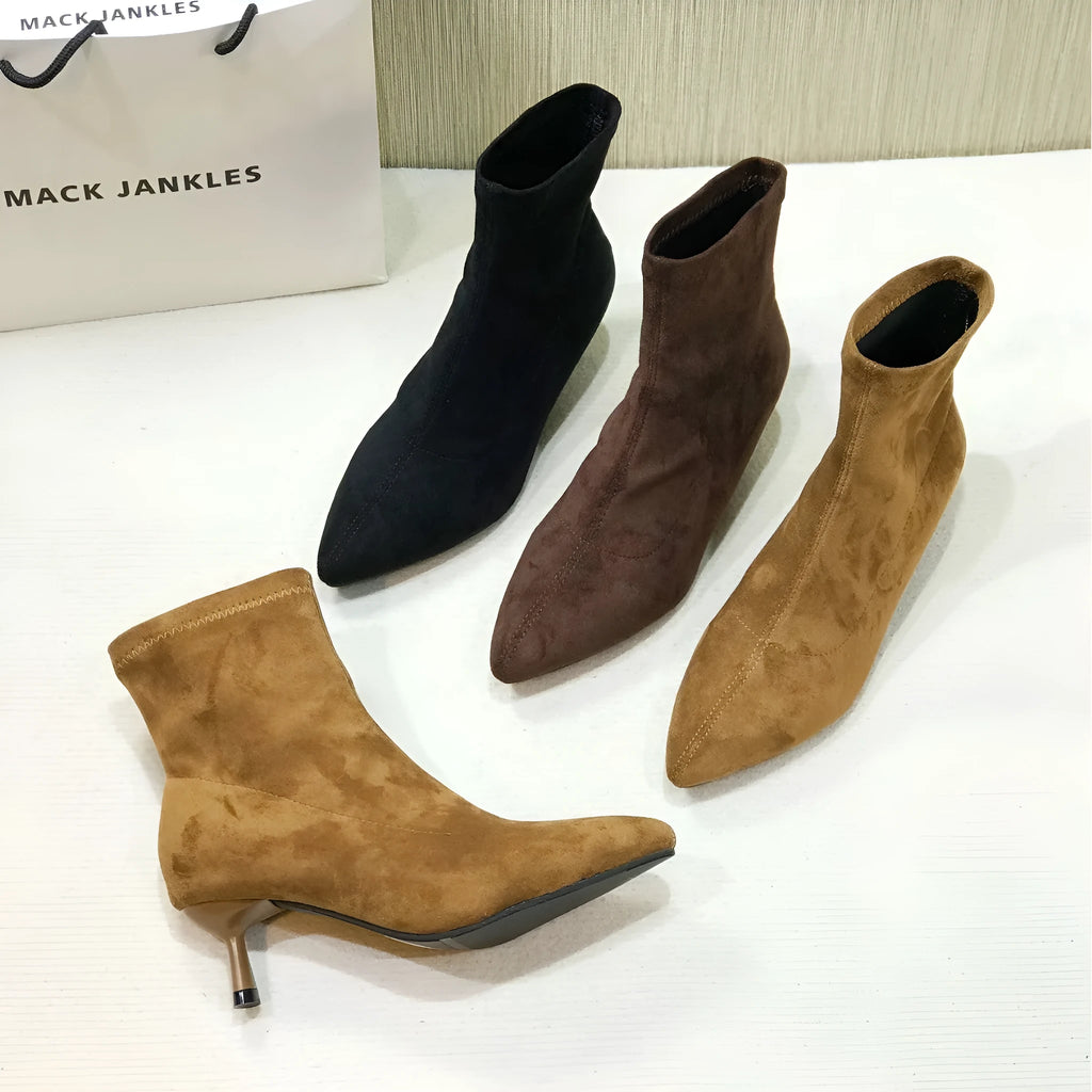 Black pointed toe women's ankle boots with a high stiletto heel on a rubber sole.