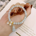 Close-up of a natural emerald jade bracelet with a detailed pearl jade gourd charm pendant.