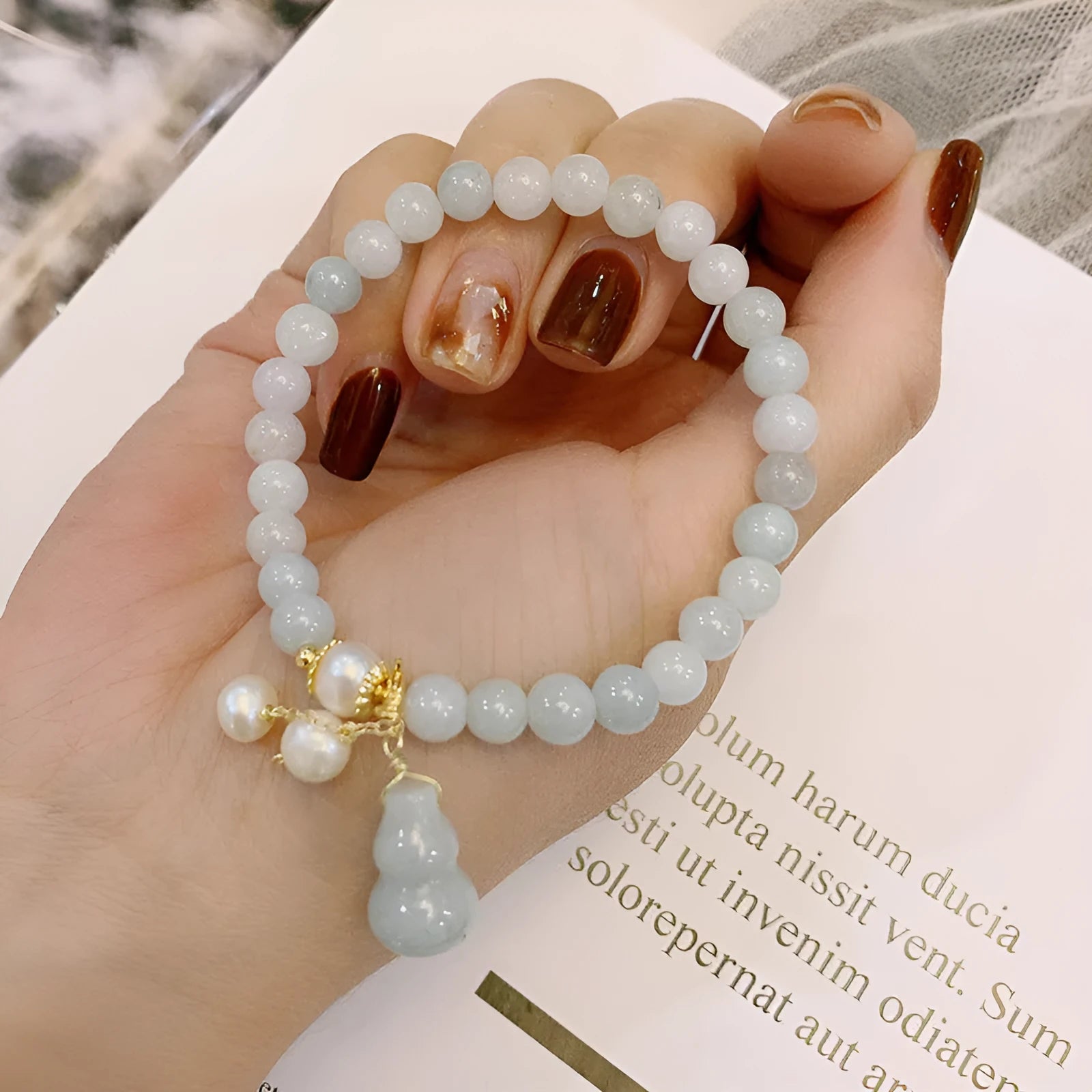 Close-up of a natural emerald jade bracelet with a detailed pearl jade gourd charm pendant.