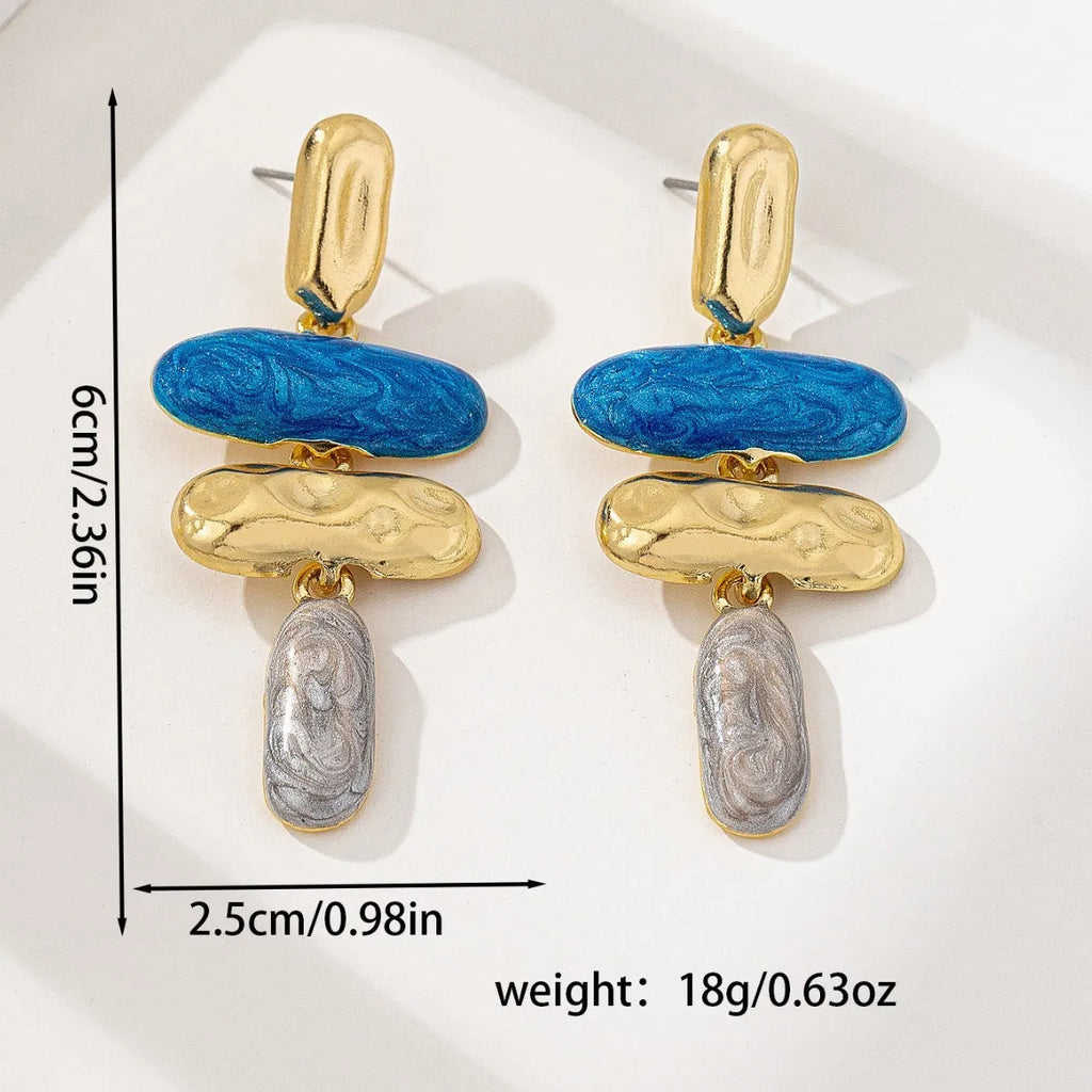 A pair of simple geometric stud earrings with a multicolour electroplated finish on a white background.