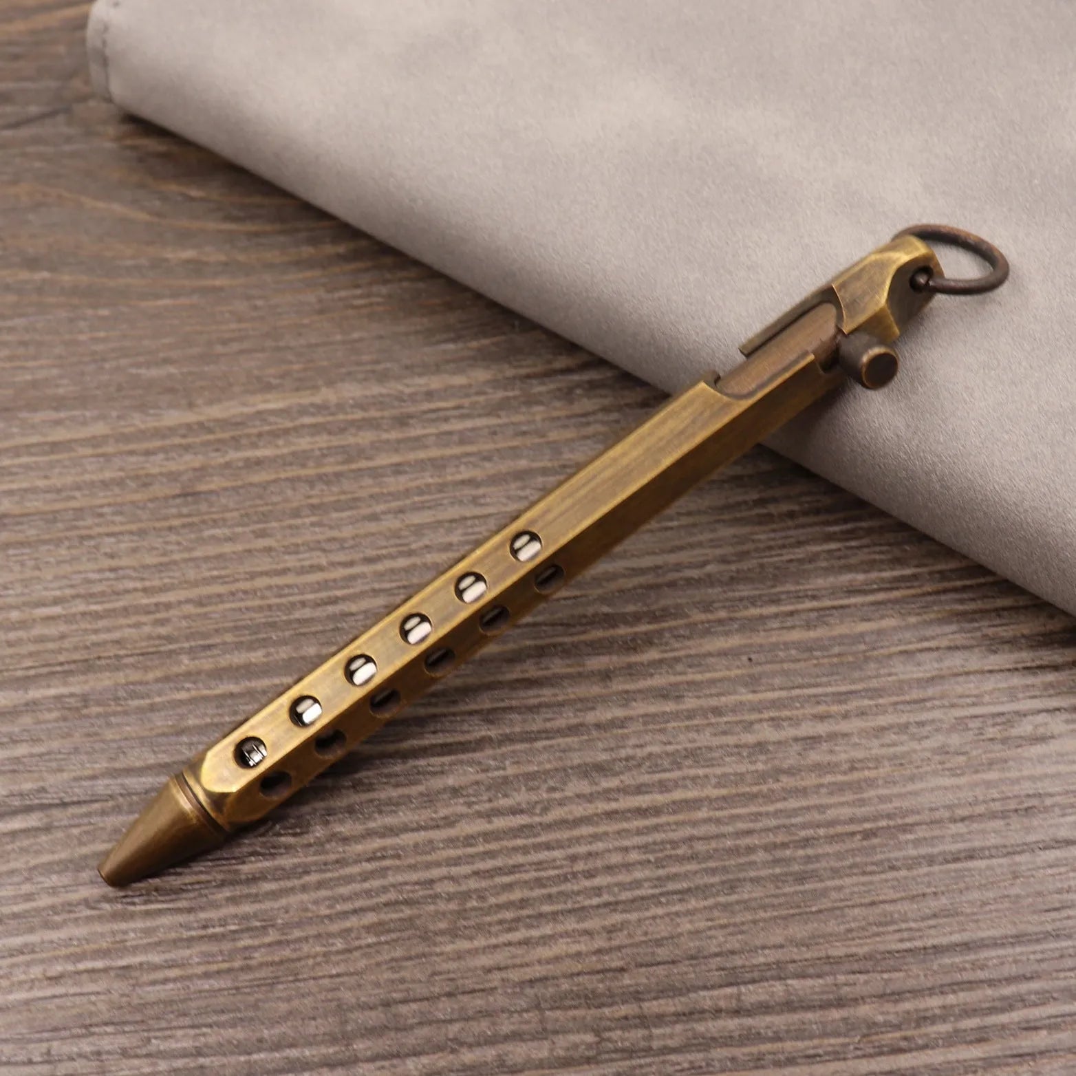 Retro brass tactical pen with cylindrical barrel and six-ring grip, shown with press mechanism extended