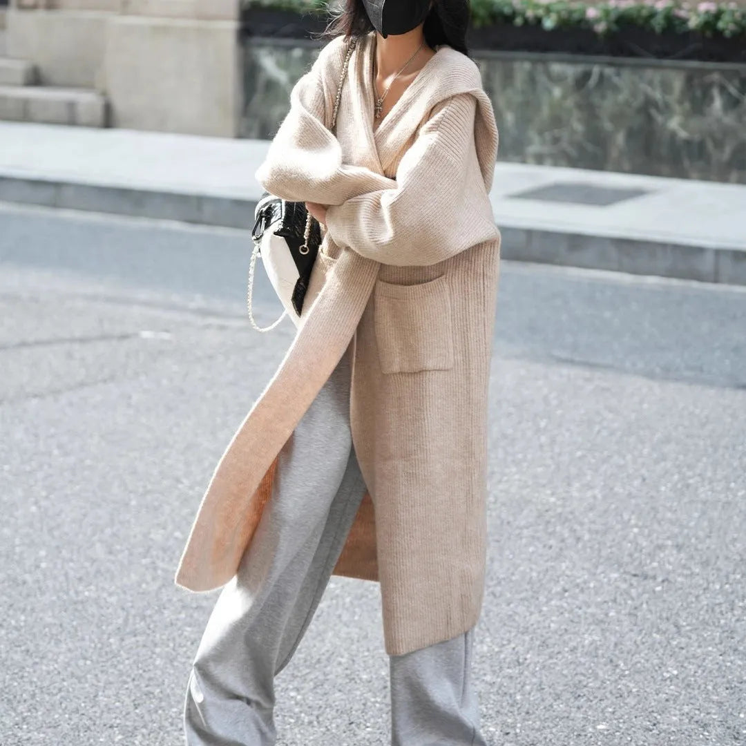 Long grey knitted hooded cardigan trench coat on a hanger, showing loose fit and long sleeves.