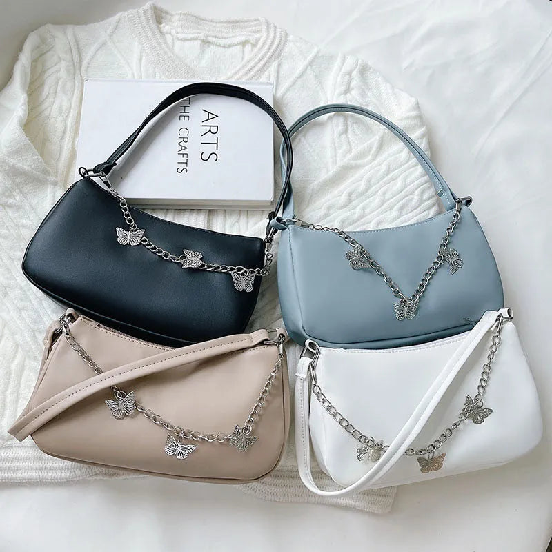 Women's black PU leather crossbody bag with butterfly chain shoulder strap showing internal phone pocket