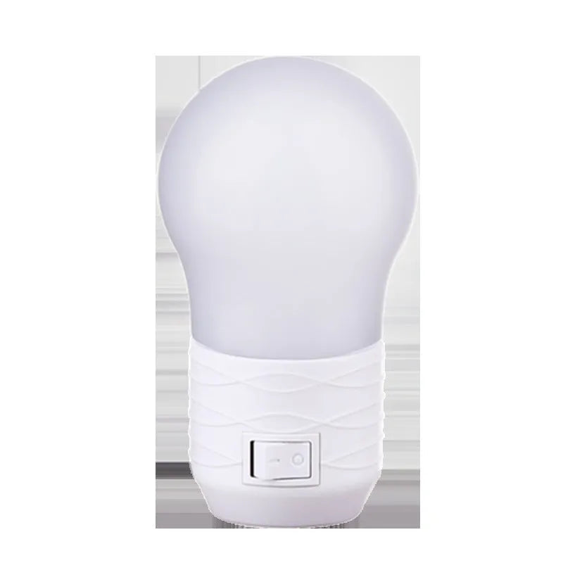 Plug-in bedside baby night light in white shell with modern round design on a table.