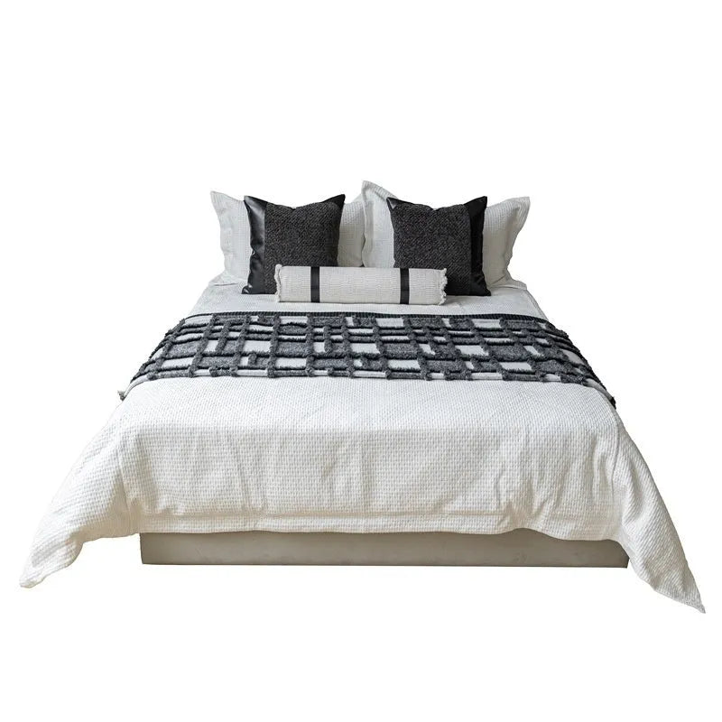 Modern minimalist plaid bed runner set with blanket, pillowcase, and round leather pillow on a bed