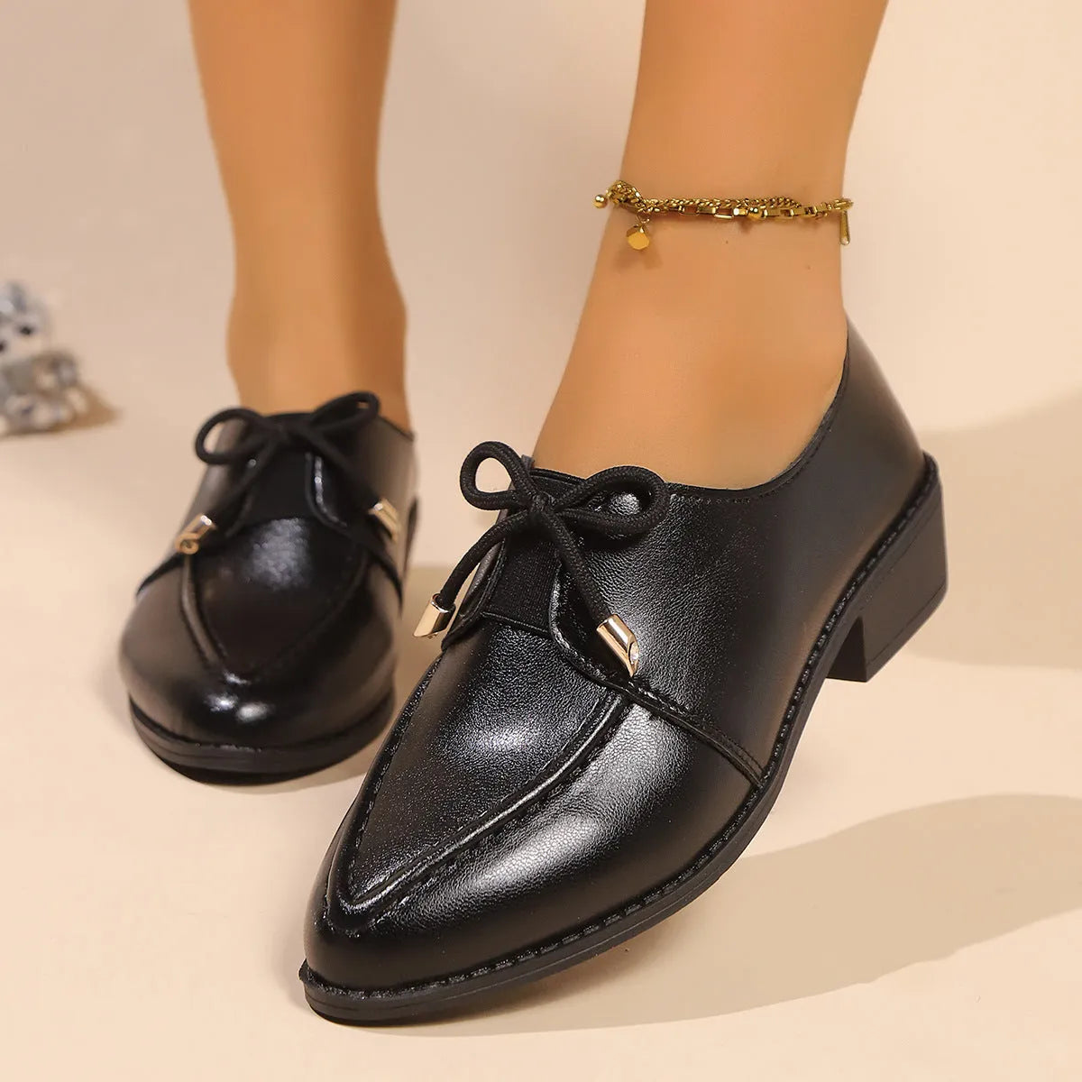 Women's British-style leather-look shoes with decorative bow detail on pointed toe