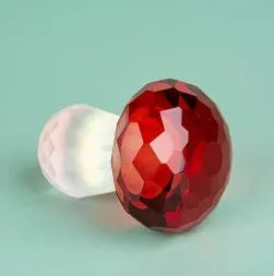 Set of four colourful crystal mushroom decorations in transparent, green, red, and yellow on a white background.