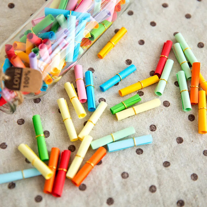 Assorted coloured miniature paper scrolls for drift bottle messages, showing pre-punched hole.