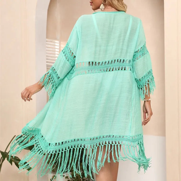 Yellow hand-crocheted women's beach cardigan with tassel detail on a hanger.