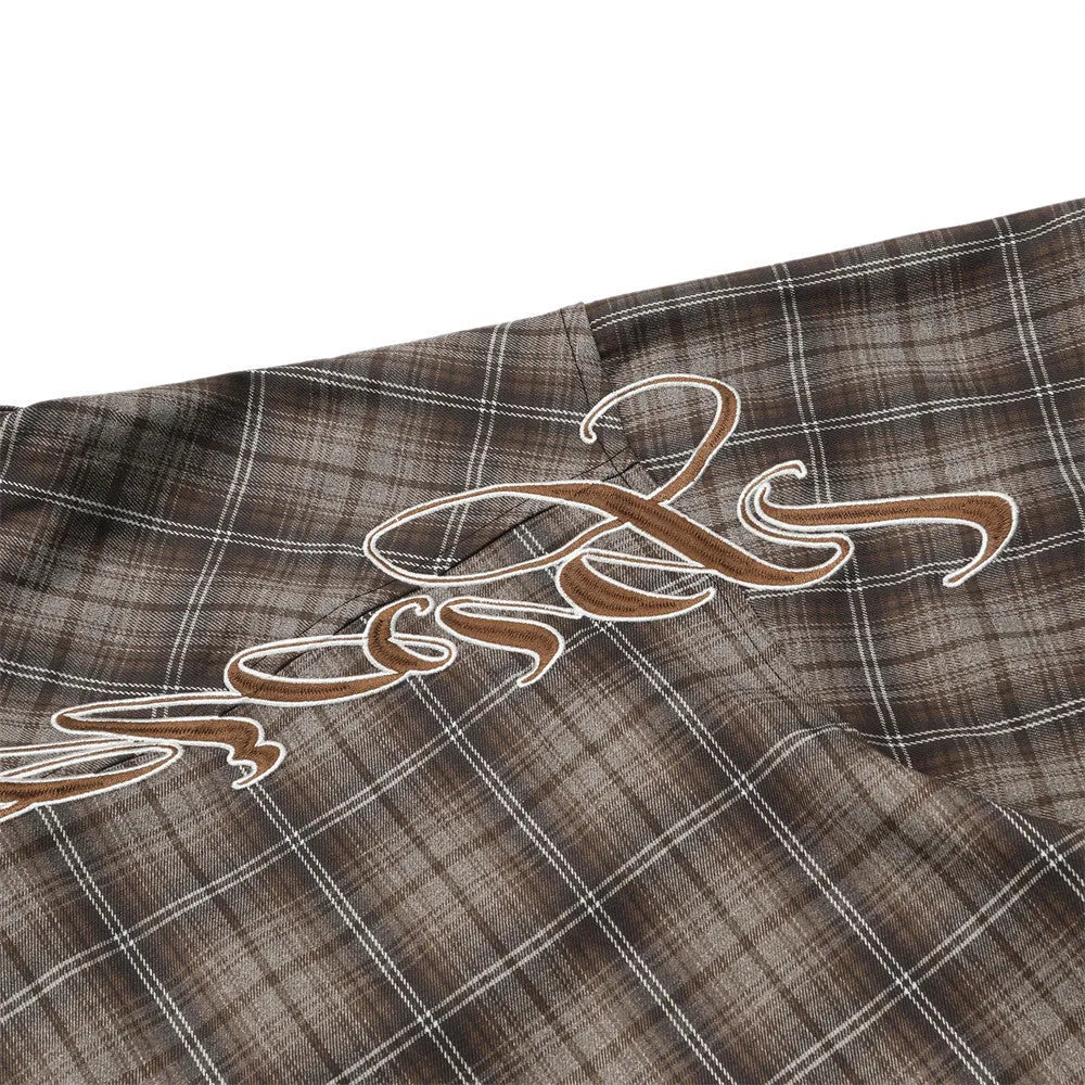 Man wearing a black and brown plaid short sleeve shirt with embroidered letter on lapel