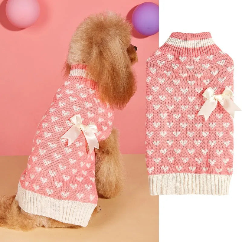Small dog wearing a pink acrylic sweater with a bow and love heart design in ins style