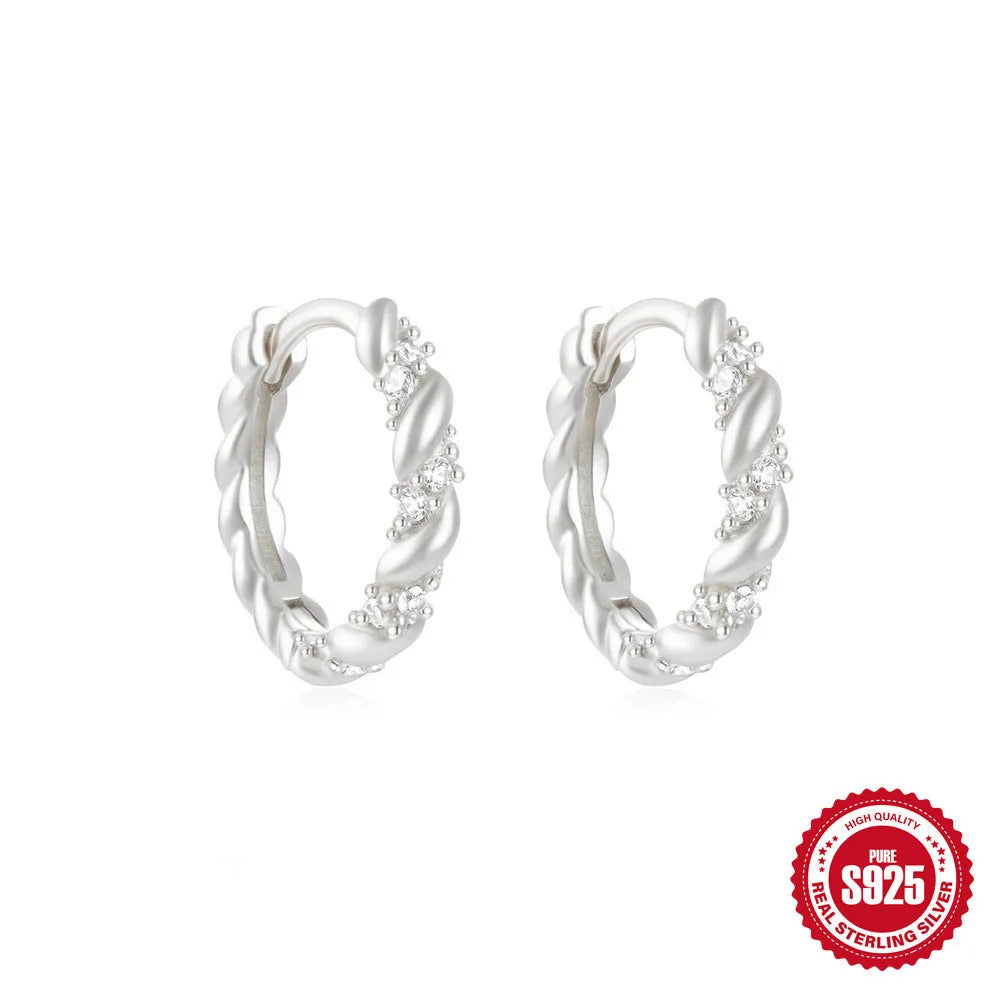 A pair of small, round, geometric stud earrings made of sterling silver with an electroplated finish.
